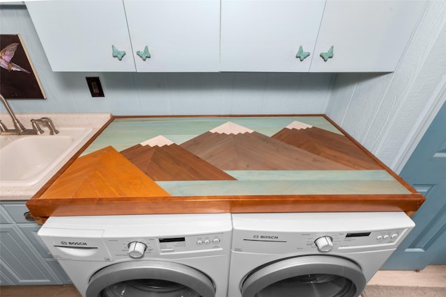 clothes washing area with cabinets, sink, and washer and dryer