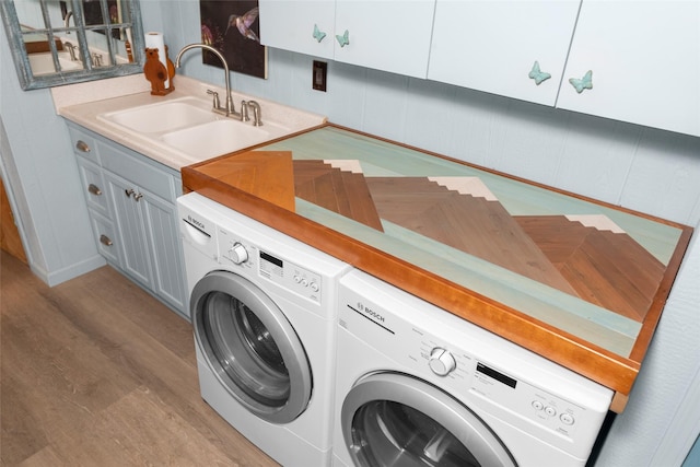 laundry room featuring cabinets, sink, washer and clothes dryer, and light hardwood / wood-style floors