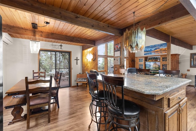 dining space with a notable chandelier, a healthy amount of sunlight, light wood-type flooring, and an AC wall unit