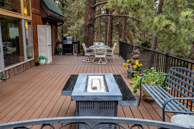 wooden deck featuring area for grilling and an outdoor fire pit