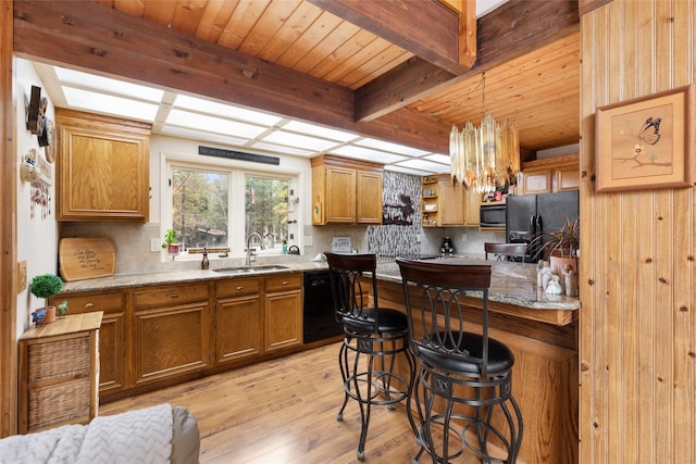 kitchen with sink, hanging light fixtures, light hardwood / wood-style floors, decorative backsplash, and black appliances