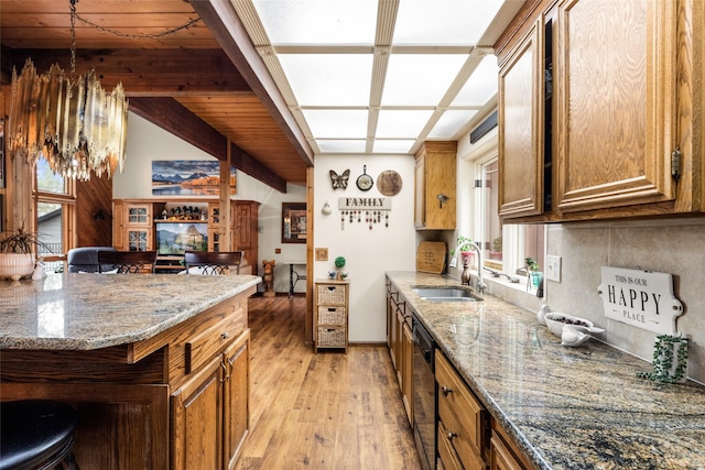 kitchen featuring sink, beam ceiling, black dishwasher, light hardwood / wood-style floors, and stone countertops