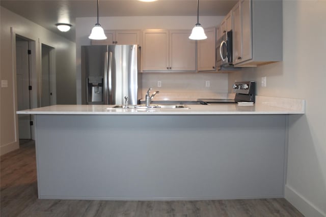 kitchen featuring hanging light fixtures, kitchen peninsula, sink, and appliances with stainless steel finishes