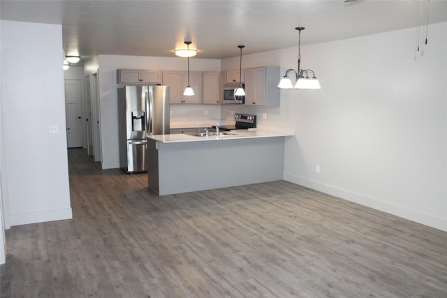 kitchen featuring gray cabinetry, hanging light fixtures, stainless steel appliances, dark hardwood / wood-style flooring, and kitchen peninsula