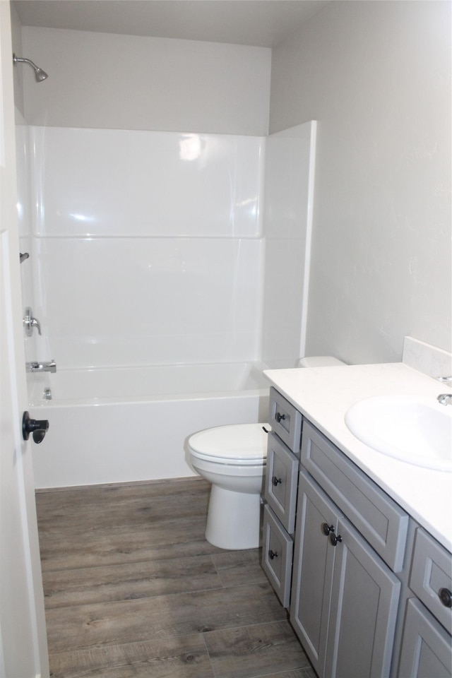 full bathroom with wood-type flooring, vanity, shower / bath combination, and toilet