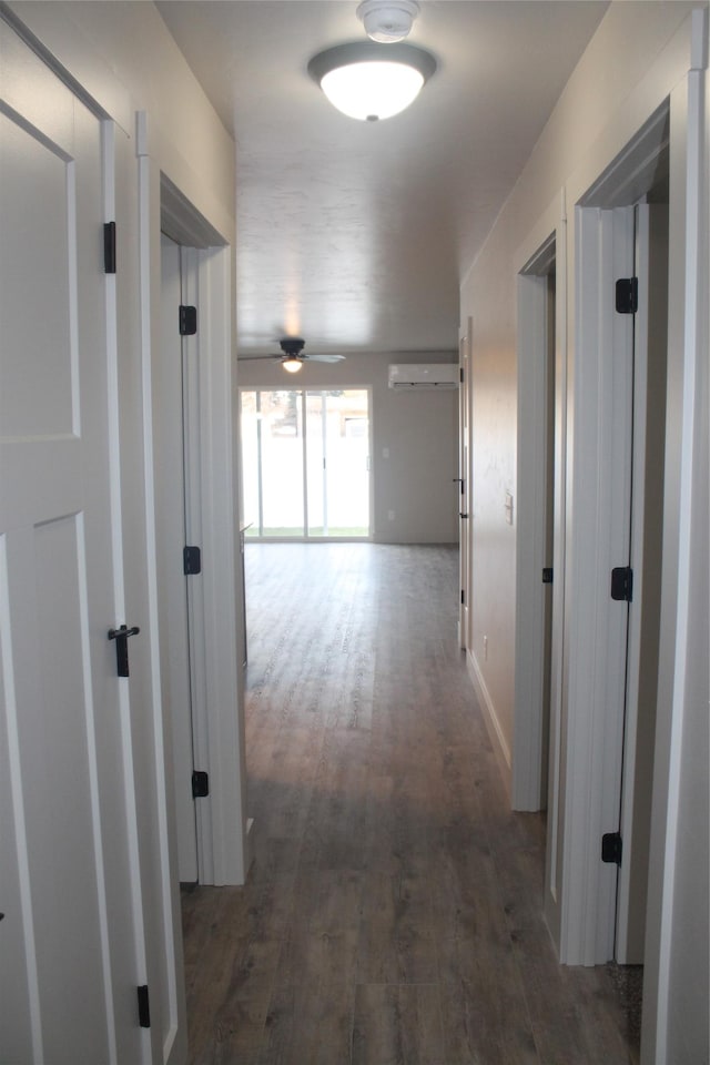 corridor with a wall mounted air conditioner and dark wood-type flooring