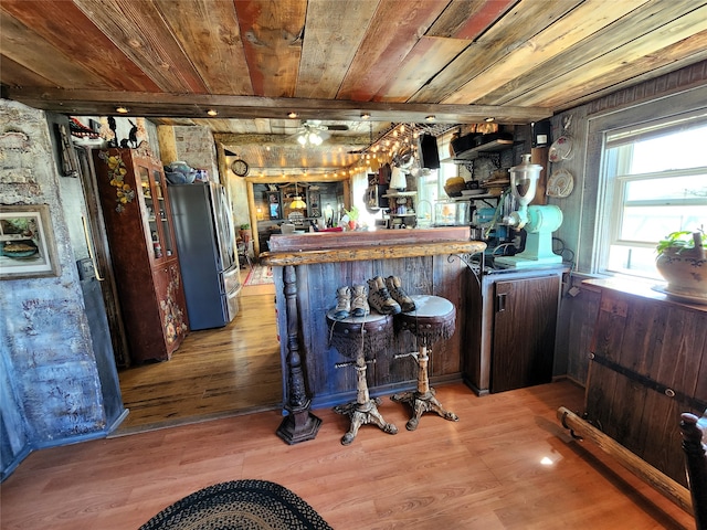 bar with light hardwood / wood-style floors, dark brown cabinetry, wooden ceiling, and fridge