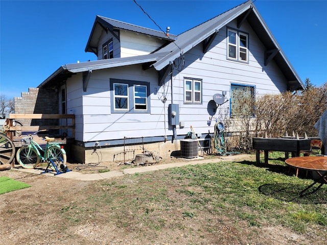 back of house with central AC unit and a lawn