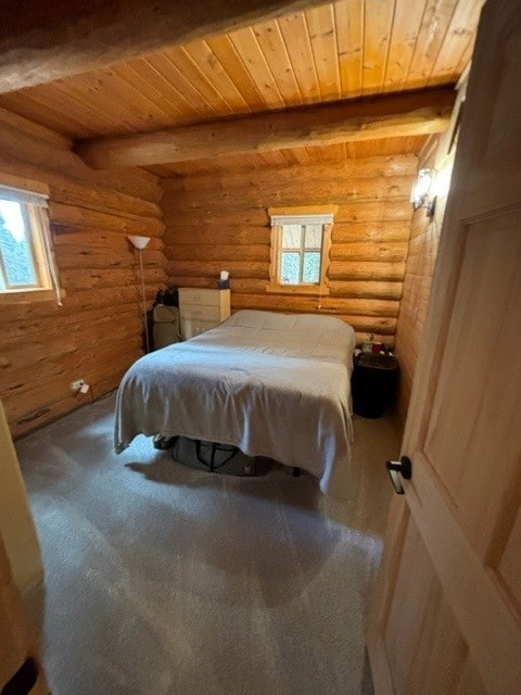 unfurnished bedroom featuring beamed ceiling, multiple windows, and rustic walls