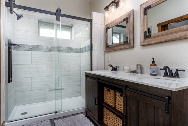 bathroom with a shower with shower door and dual bowl vanity