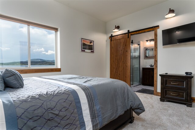 carpeted bedroom featuring a barn door and ensuite bathroom