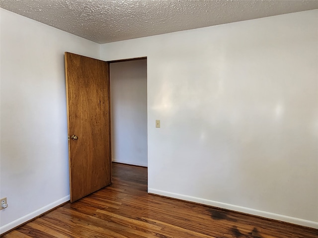 spare room with a textured ceiling and dark hardwood / wood-style floors