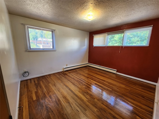 empty room featuring wood-type flooring, a baseboard heating unit, and a textured ceiling