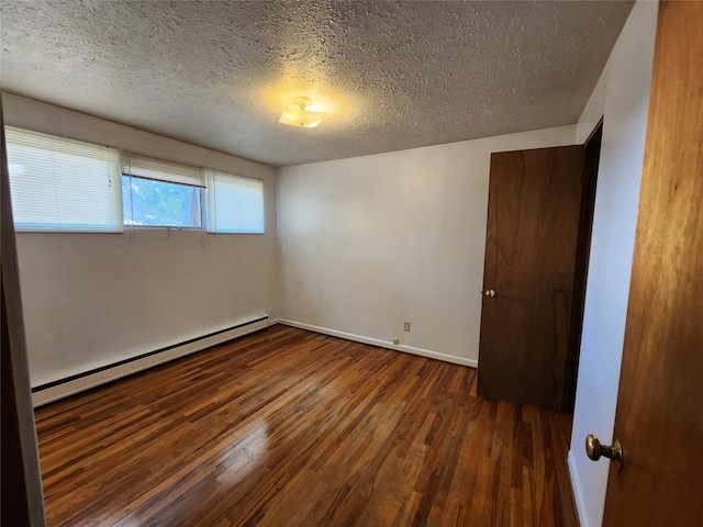 spare room featuring a baseboard heating unit, dark hardwood / wood-style floors, and a textured ceiling