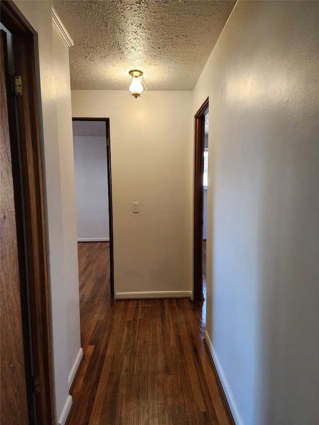 hallway featuring dark wood-type flooring and a textured ceiling