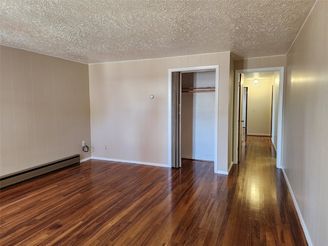 unfurnished bedroom with a closet, a baseboard heating unit, dark hardwood / wood-style flooring, and a textured ceiling