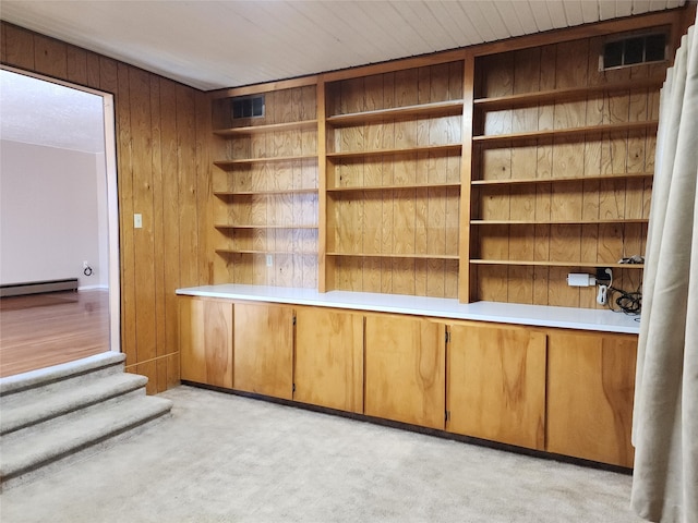 unfurnished office with wood walls, light colored carpet, and a baseboard radiator