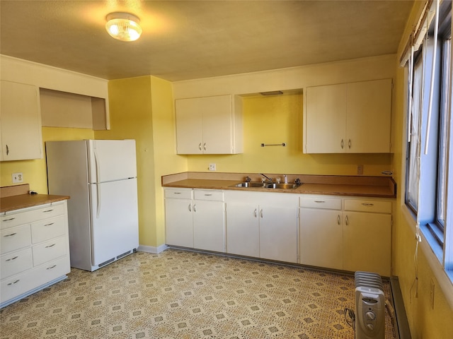 kitchen featuring sink, white fridge, and white cabinetry