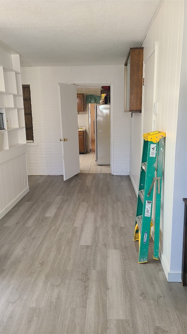 unfurnished room with a textured ceiling and light hardwood / wood-style flooring