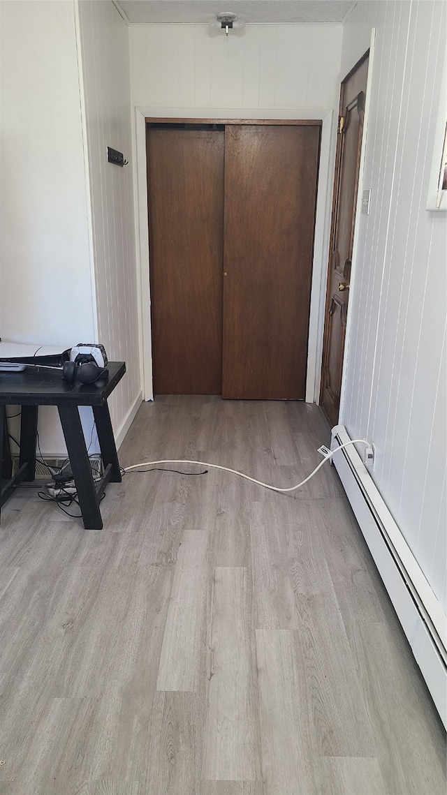 corridor with a baseboard radiator and light hardwood / wood-style floors