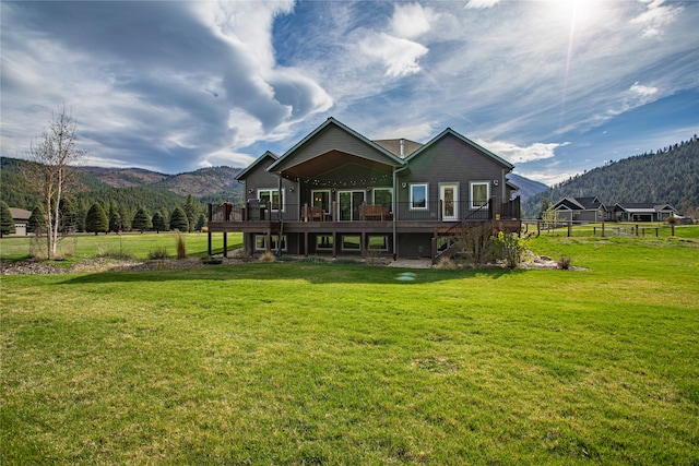 back of house with a yard and a deck with mountain view