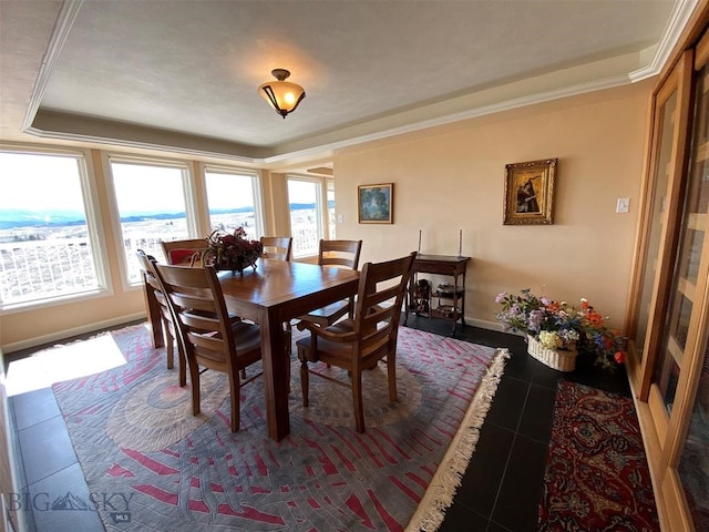 dining area with plenty of natural light, dark tile flooring, crown molding, and a raised ceiling