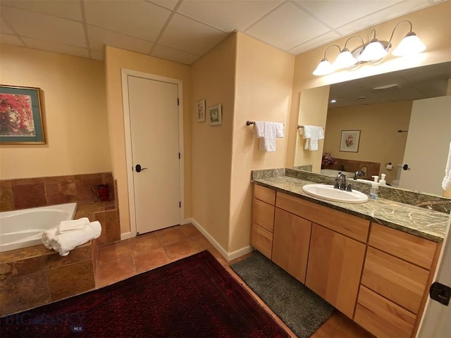 bathroom with tile flooring, a drop ceiling, oversized vanity, and a relaxing tiled bath