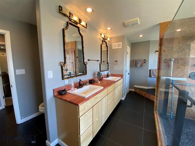 bathroom featuring tile flooring, oversized vanity, toilet, and dual sinks