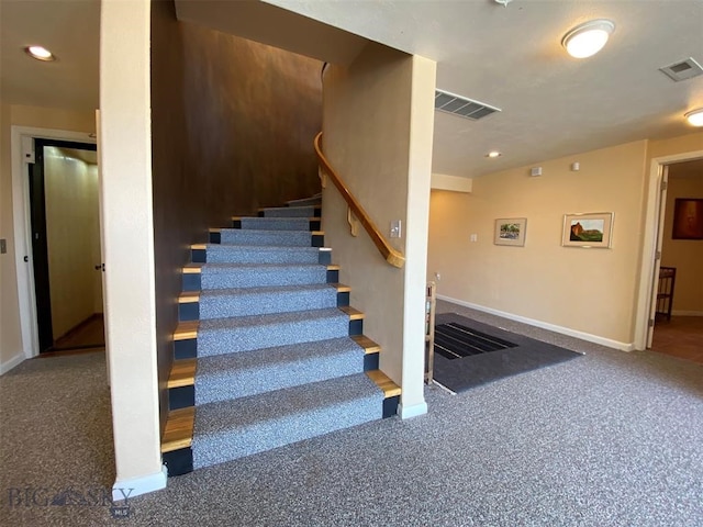 stairs featuring dark colored carpet