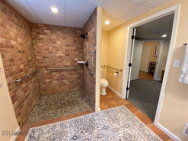 bathroom featuring tile floors, a paneled ceiling, toilet, and tiled shower