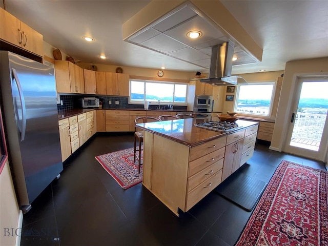 kitchen with dark tile floors, a healthy amount of sunlight, stainless steel appliances, and island range hood