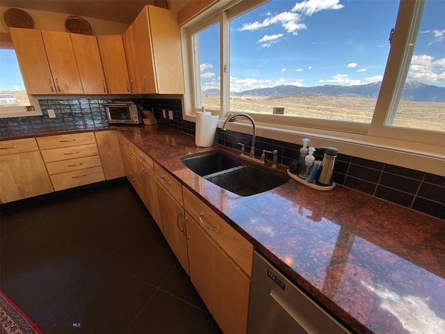 kitchen featuring stainless steel dishwasher, sink, a mountain view, and backsplash