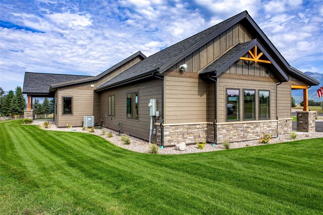 114 Pheasant Ridge Ct, Polson, MT 59860 - back of house featuring central AC unit, a yard, stone siding, and a shingled roof