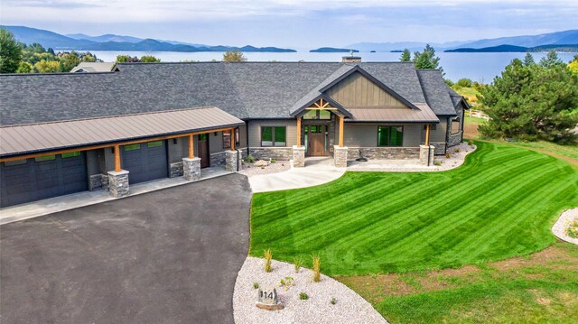 114 Pheasant Ridge Ct, Polson, MT 59860 - view of front facade featuring a mountain view, stone siding, covered porch, and a front lawn