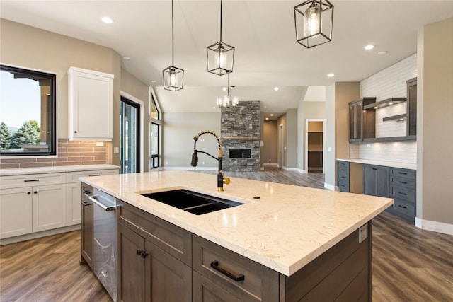 kitchen featuring dark hardwood / wood-style floors, sink, white cabinets, backsplash, and a center island with sink