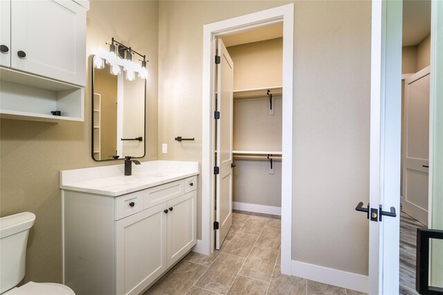 114 Pheasant Ridge Ct, Polson, MT 59860 - full bathroom with toilet, vanity, a walk in closet, baseboards, and tile patterned flooring