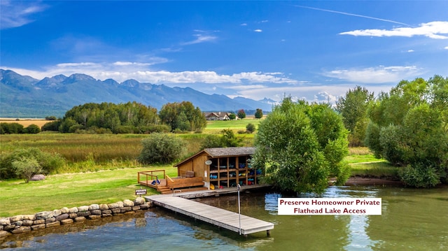 view of dock with a water and mountain view and a yard