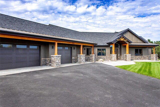 114 Pheasant Ridge Ct, Polson, MT 59860 - view of front facade featuring stone siding, driveway, and an attached garage