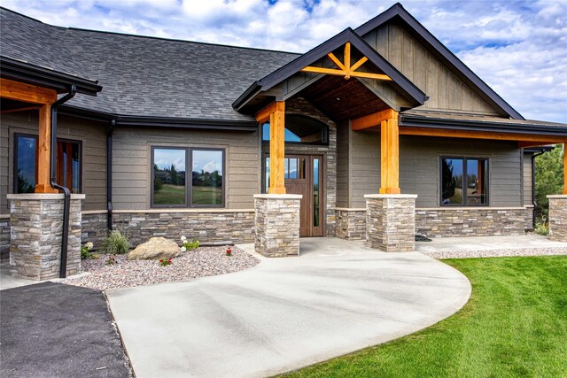 114 Pheasant Ridge Ct, Polson, MT 59860 - view of front of house featuring stone siding, a shingled roof, board and batten siding, and a front yard
