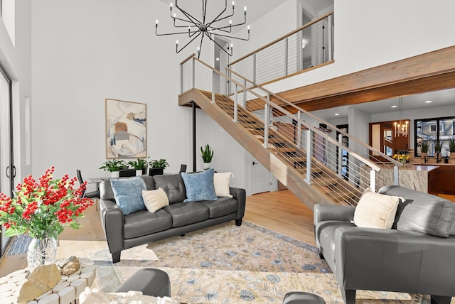 living room featuring a chandelier, a high ceiling, stairway, and light wood-style flooring