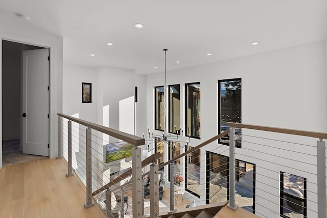 hallway featuring recessed lighting, light wood-style flooring, and an upstairs landing