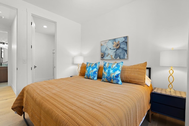 bedroom featuring light wood-style flooring and ensuite bath