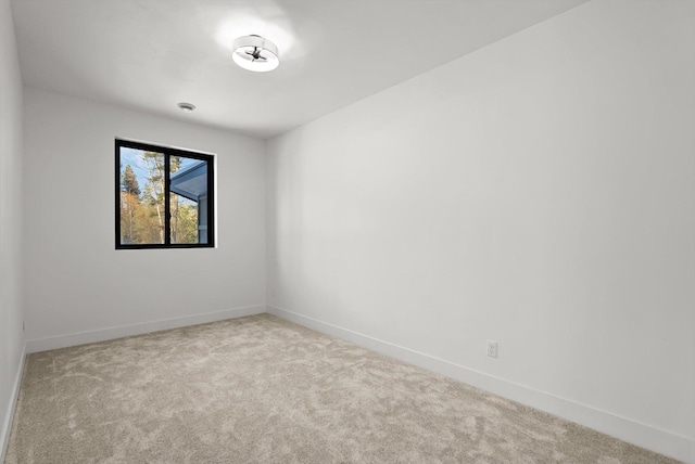 spare room with light carpet and baseboards