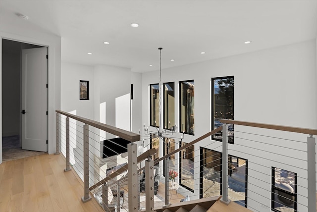 corridor with light wood-type flooring, an upstairs landing, and recessed lighting