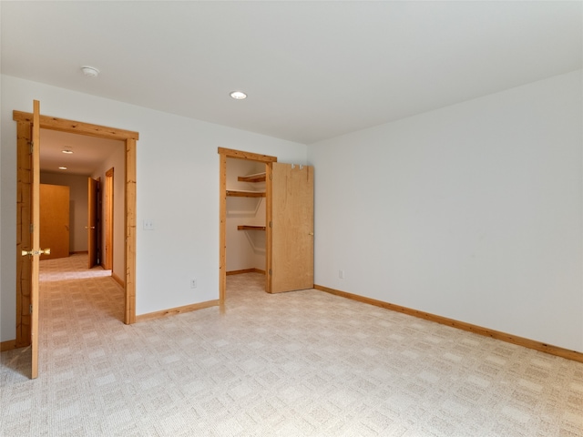 unfurnished bedroom with light colored carpet, a walk in closet, and a closet