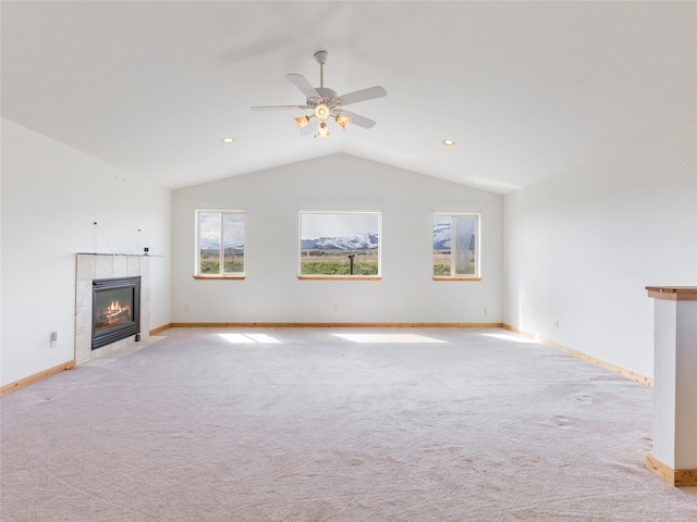 unfurnished living room featuring carpet flooring, vaulted ceiling, ceiling fan, and a tile fireplace