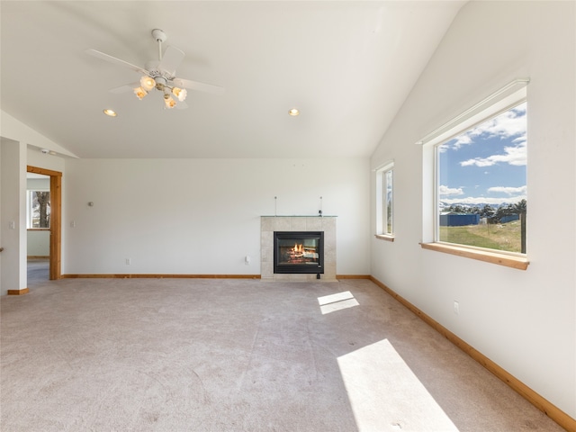 unfurnished living room featuring lofted ceiling, a tile fireplace, ceiling fan, and light colored carpet