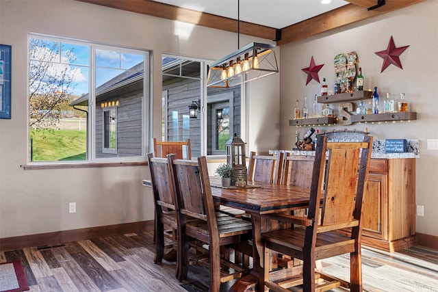 dining space with beamed ceiling, a wealth of natural light, and hardwood / wood-style flooring