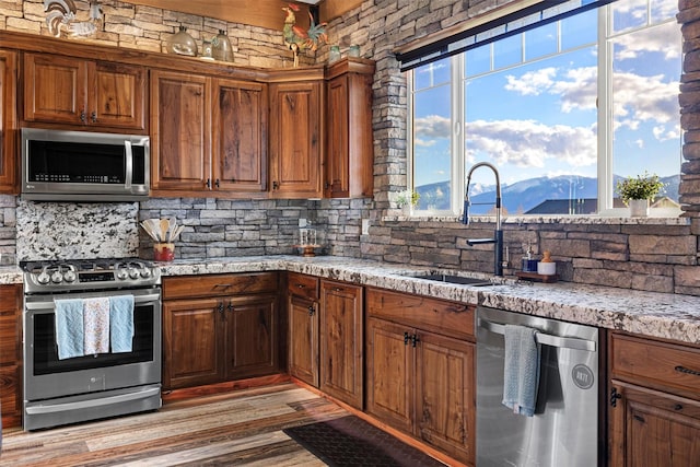 828AND806 Corvallis Hills Dr, Corvallis, MT 59828 - kitchen featuring appliances with stainless steel finishes, tasteful backsplash, a mountain view, light wood-type flooring, and light stone counters