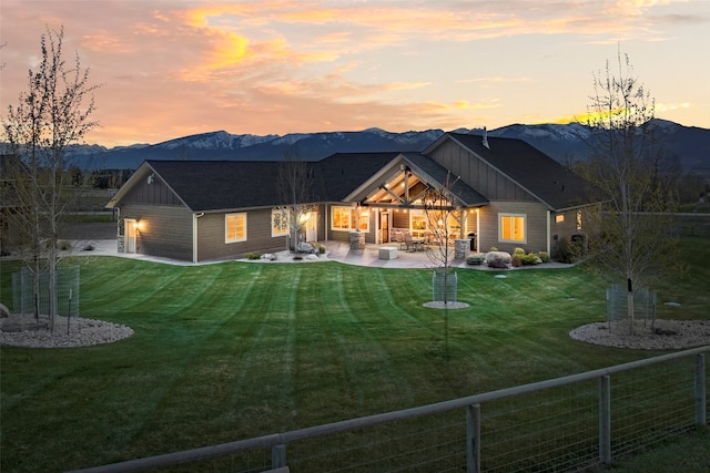 back house at dusk featuring a mountain view, a yard, and a patio